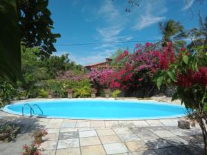 a swimming pool in front of a house with flowers at Casa Laranja in Cascavel