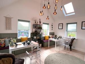 uma sala de estar com mesas, cadeiras e janelas em Thistledown Lodge em Fethard on Sea