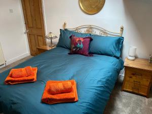 un letto blu con due cuscini arancioni sopra di Top O’ Th’ House . Hebden Bridge a Hebden Bridge