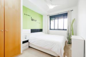 1 dormitorio con cama blanca y pared verde en Lujoso apartamento de dos habitaciones en la playa de Canet, en Canet de Berenguer