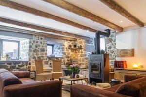 a living room with leather furniture and a stone fireplace at Lo d Ici, Gite de groupe et de Caractere in Nasbinals