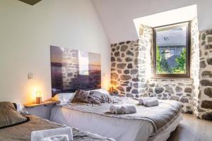 two beds in a room with a stone wall at Lo d Ici, Gite de groupe et de Caractere in Nasbinals