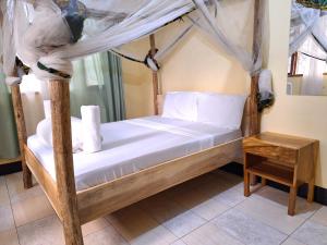 1 dormitorio con cama con dosel y sábanas blancas en Hill View Garden Hotel, en Moshi
