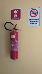 um hidrante vermelho ao lado de uma placa na parede em Hostel Office- Hospedagem Climatizada quartos e apartamentos privativos em Extrema