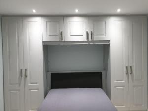 a white bedroom with a bed and white cabinets at Cozy Studio Apartment in Dublin