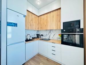 eine Küche mit weißen Geräten und Holzschränken in der Unterkunft Кок Жайлау apartament in Astana