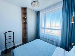um quarto com uma cama e uma grande janela em Кок Жайлау apartament em Astana