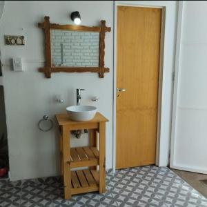 baño con lavabo y puerta de madera en Casa Olivia Habitación privada en Alta Gracia