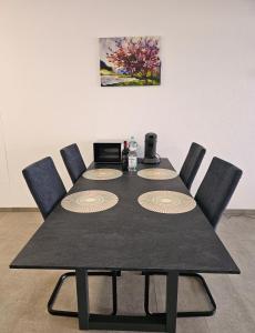a dining room table with chairs and a black table with a picture at MY HOME EUROPAALLEE 26 in Villingen-Schwenningen
