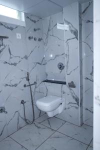 y baño blanco con aseo y ducha. en Hotel Lorven en Tirupati