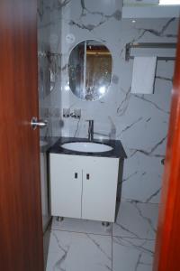 y baño con lavabo blanco y espejo. en Hotel Lorven en Tirupati