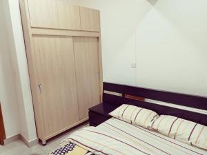 Schlafzimmer mit einem Bett mit einem Kopfteil aus Holz und einem Schrank in der Unterkunft Simon's Place in Kigali