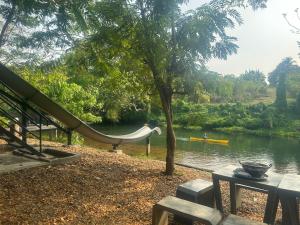 een park met een glijbaan en een boot in het water bij ชลลดา ริเวอร์ โฮมสเตย์ แก่งกระจาน in Ban Wang Malako