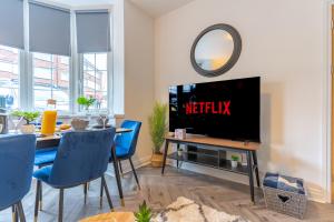 a living room with a tv and a table with blue chairs at New 4BR family home sleeps 8 -10 people with free parking and contractors welcome in Birmingham