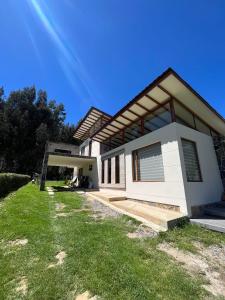 a white house with a grassy yard in front of it at Casa de Campo Moderna Ubaté - Sector La Laja in Ubaté