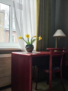 a table with a vase with yellow flowers on it at Muzeja apartamenti in Rīga