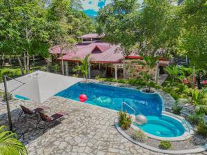 a swimming pool with an umbrella and a house at Villa Sebastiana Bungalows in Tarapoto