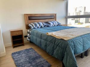 1 dormitorio con 1 cama con edredón azul y ventana en Departamento ñuñoa, en Santiago