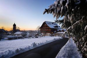 a building covered in snow next to a street at Hotel Kurhaus Heiligkreuz in Heiligkreuz