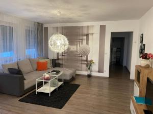 ein Wohnzimmer mit einem Sofa und einem Kronleuchter in der Unterkunft Apartments Kastanienbaum in Herzogenaurach