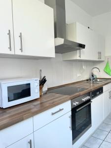 een keuken met witte kasten en een magnetron bij Stay Westend in Wetzlar