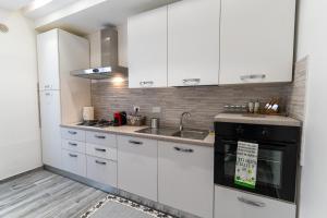 a kitchen with white cabinets and a sink and a stove at L'Onda Affittacamere in Civitavecchia
