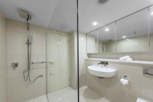 ein Badezimmer mit Dusche, Waschbecken und Spiegel in der Unterkunft Oaks Darwin Elan Hotel in Darwin
