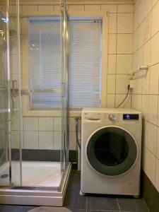 uma máquina de lavar roupa no canto de uma casa de banho em Perfekt til Palmesus! Parkering inkludert. em Kristiansand