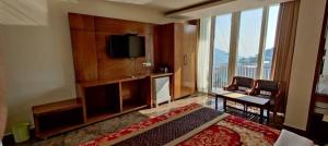 a hotel room with a bed and a flat screen tv at HOTEL INDIA HOUSE in Dharamshala