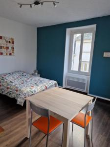 Un dormitorio con una cama y una mesa y sillas. en Studio proche rectorat et théâtre de l'union, en Limoges