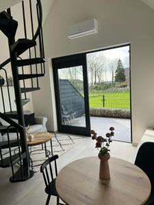 een woonkamer met een tafel, een trap en een raam bij Veldt's huisje in Limmen