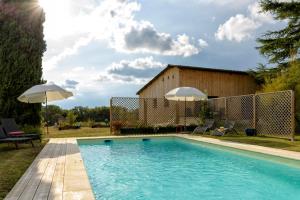 ein Pool mit zwei Sonnenschirmen im Hof in der Unterkunft au Mas de Garet - Chambre d'hotes de Charme in Pinsac