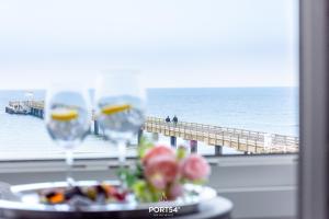 una mesa con 2 copas de vino y vistas a un muelle en Ferienwohnung Relax Happy Schönberger Strand, en Schönberger Strand