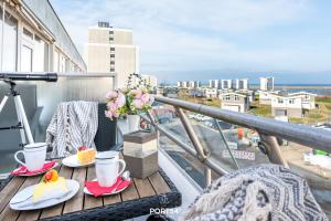 a table with two cups of coffee and flowers on a balcony at Ferienwohnung Marina Apartment 9403 in Marina Wendtorf in Wendtorf