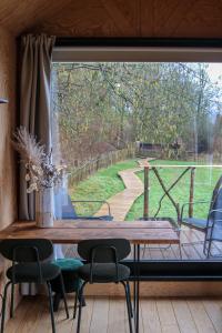 Habitación con mesa, sillas y ventana grande. en Ekko tiny house, en Philippeville
