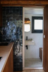 una cocina con una pared de azulejos negros y un fregadero en Ekko tiny house, en Philippeville