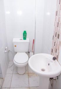 La salle de bains blanche est pourvue de toilettes et d'un lavabo. dans l'établissement Mtwapa Musical Utopia apartment, à Mombasa