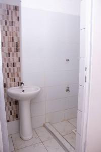 La salle de bains blanche est pourvue d'un lavabo et d'une douche. dans l'établissement Mtwapa Musical Utopia apartment, à Mombasa