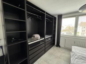 una camera da letto con armadi neri, un letto e una finestra di Moderne 2-Zimmer Wohnung im Zentrum von Wolfsburg a Wolfsburg