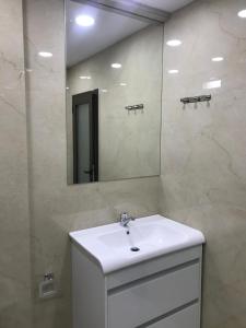 ein Badezimmer mit einem weißen Waschbecken und einem Spiegel in der Unterkunft George Hotel Rooms&Suites in Himarë