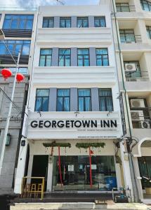 een wit gebouw met een bord voor een bruine herberg bij Georgetown Inn by Sky Hive in George Town