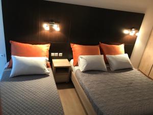 1 Schlafzimmer mit 2 Betten mit orangefarbenen und weißen Kissen in der Unterkunft George Hotel Rooms&Suites in Himarë