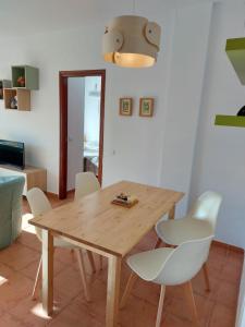 Apartamento en Islantilla Golf في إسلانتييّا: غرفة طعام مع طاولة خشبية وكراسي بيضاء