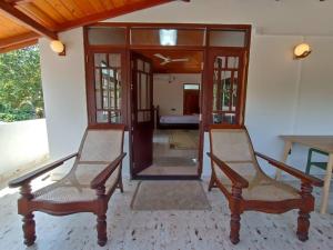two chairs in front of a room with a door at Edmon Beach Villa in Dodanduwa