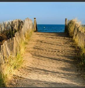 um caminho de madeira que leva ao oceano numa praia em Maison avec jardin à proximité de la plage et du canal du Midi pour 6 personnes em Portiragnes