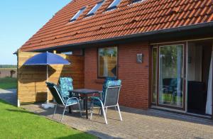 a table with chairs and an umbrella in front of a house at Ferienwohnung in Lemkenhafen auf Fehmarn in Fehmarn