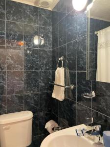 a black tiled bathroom with a toilet and a sink at Hostal Desert in San Pedro de Atacama