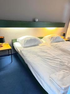 ein Schlafzimmer mit einem großen Bett mit weißen Laken und Kissen in der Unterkunft Hohegeiß Ferienwohunung - 14ter Etage mit Blick in Braunlage + 4 Fotos