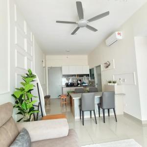 a living room with a ceiling fan and a kitchen at Amber Cove Seaview I MUJI 2BR I Game Room I 3-9pax in Melaka