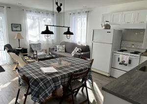 a kitchen and living room with a table and a refrigerator at Chalet Du Marais in Saint-Paulin